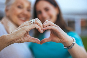 Senior and adult forming a heart with their hands — care and connection